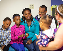 A family of five speaks with a nurse