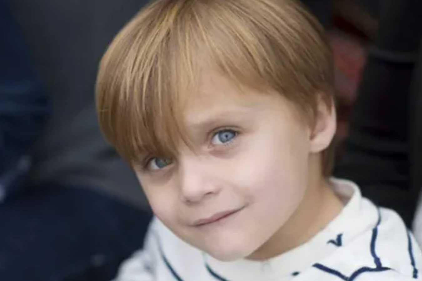 Young boy in striped shirt looking up at camera