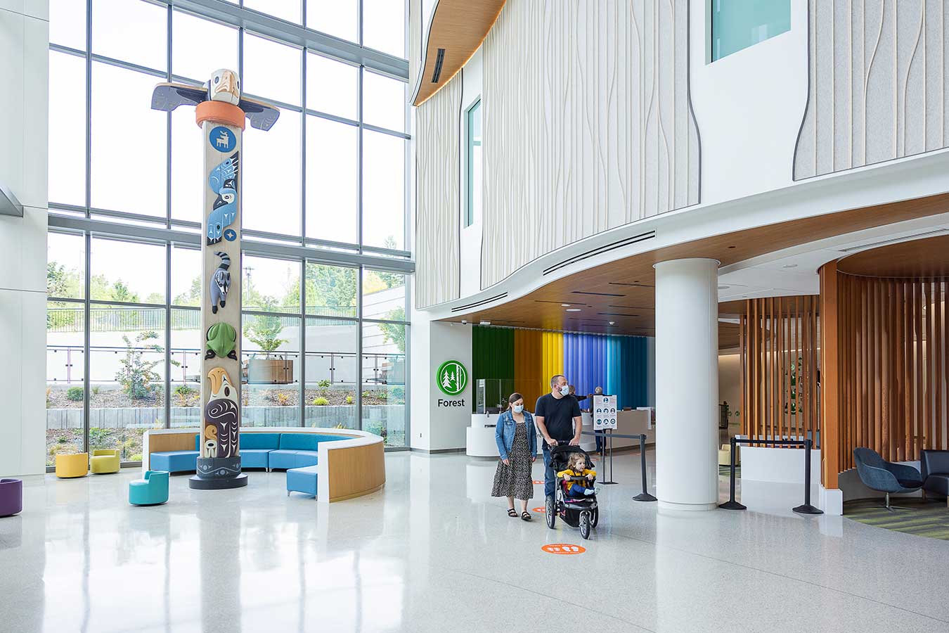 A family wearing masks walks through the lobby of Seattle Children's Forest B