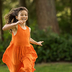 A girl in an orange dress running through a park