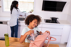 A girl packs a lunch into her backpack