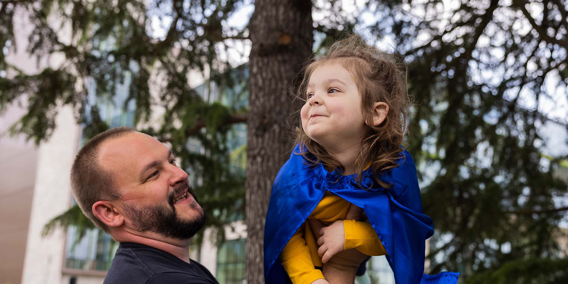 A girl is lifted in the air by her father